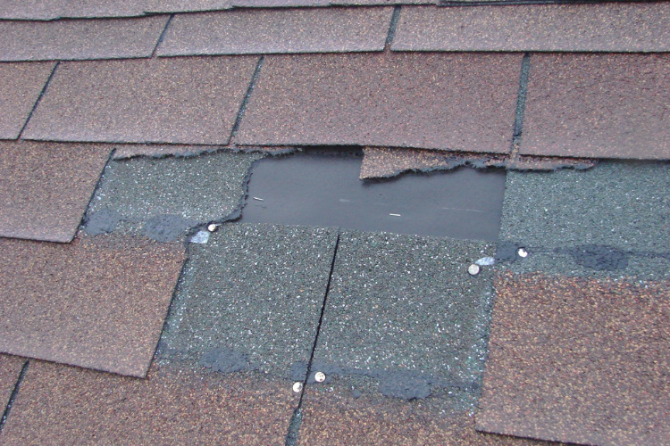 Missing shingles from wind damage on a Plymouth roof