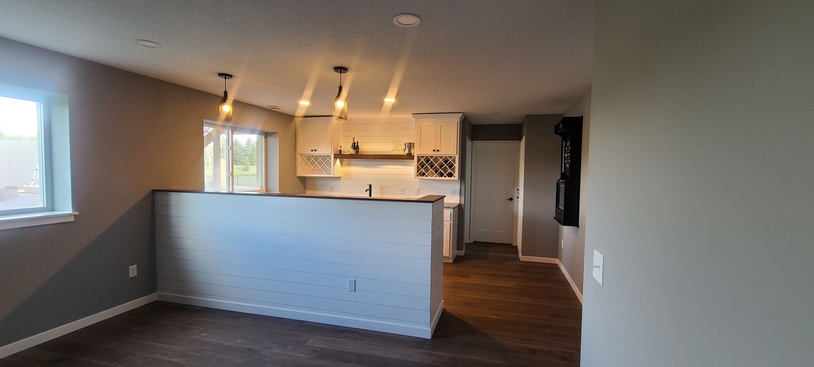 Finished basement with custom cabinetry, lighting, and peninsula bar