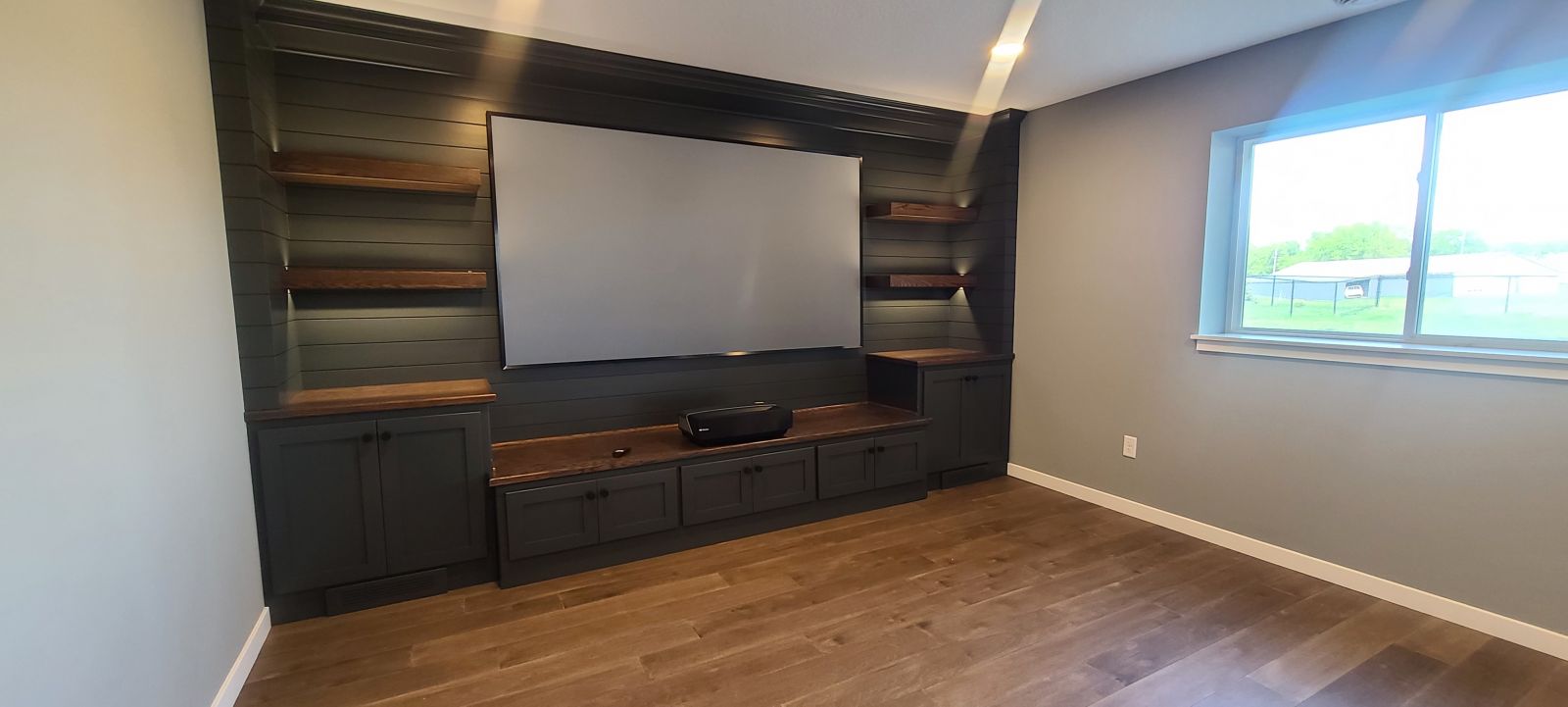 Custom basement entertainment wall with built-in cabinetry, open shelving and television space