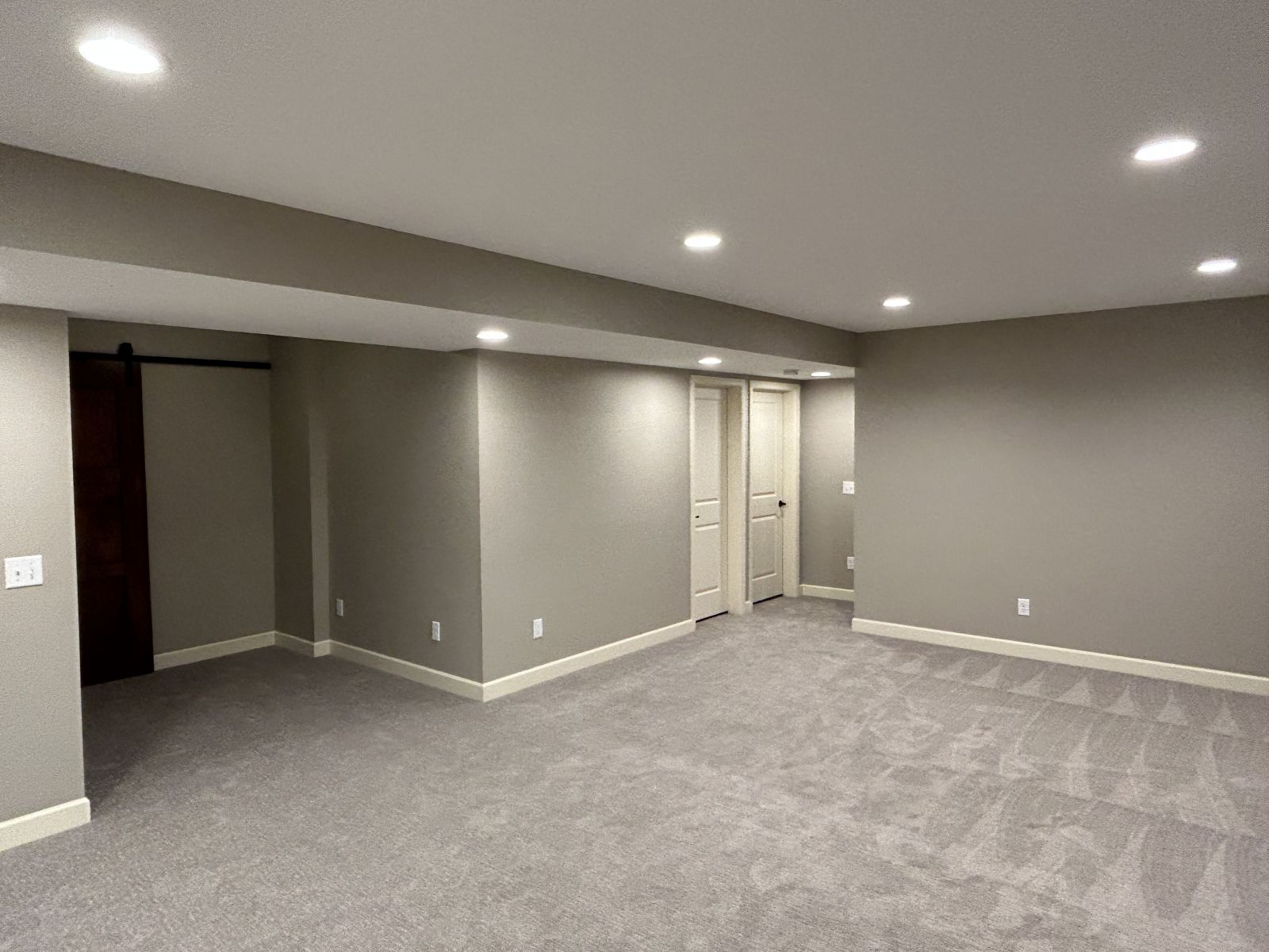 Completed basement family room with soft carpet, recessed lighting and flexible open floor space