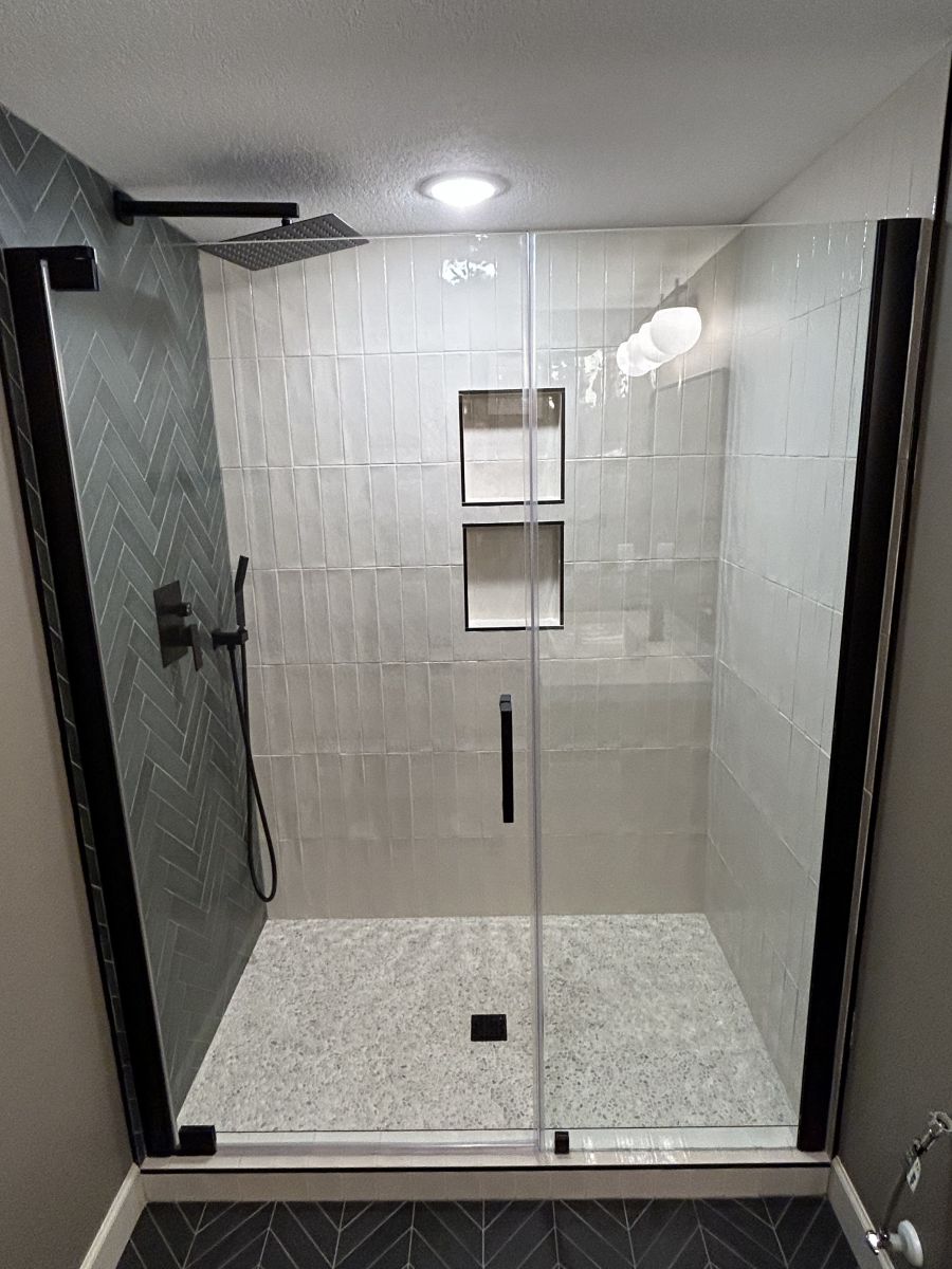 Finished basement bathroom with glass shower, tiled walls and built-in niches