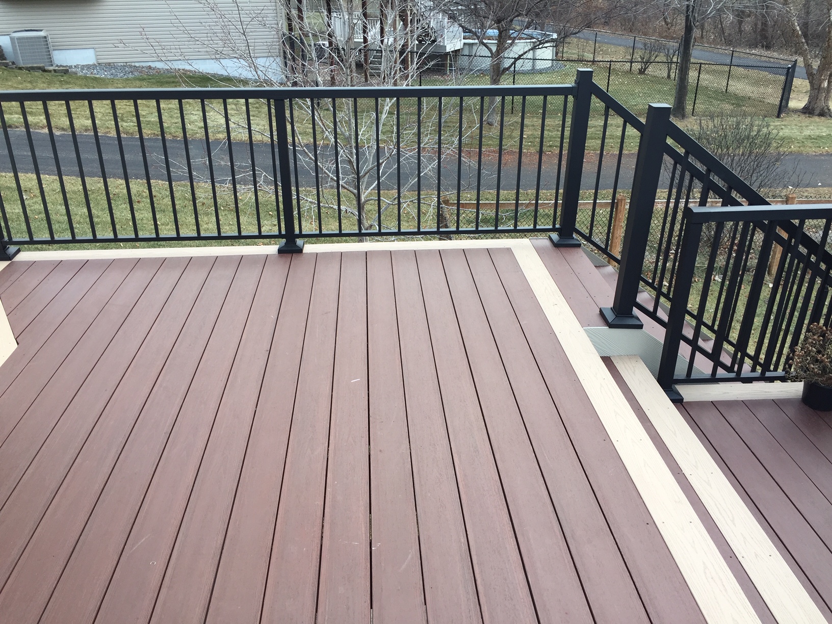 Close view of two-tone deck boards and black metal railing on a finished deck