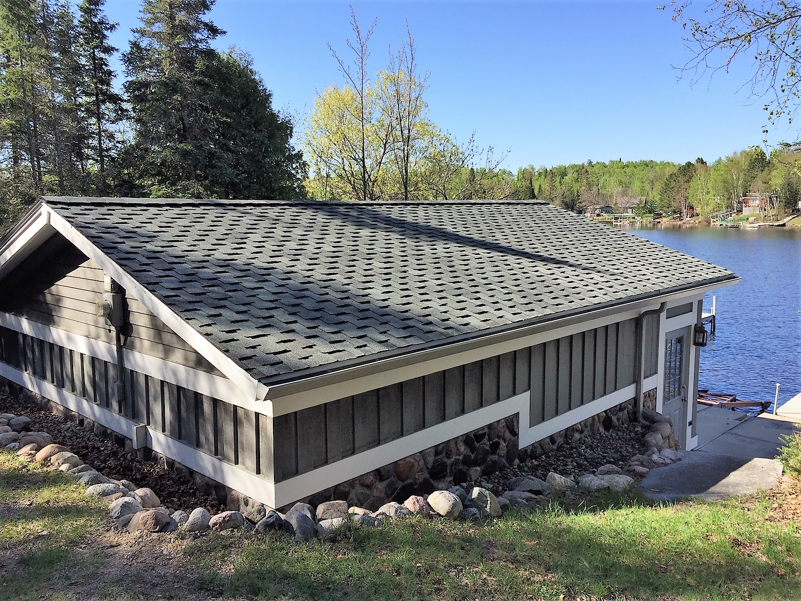 Completed asphalt-shingle roof on a lakeside Minnesota outbuilding