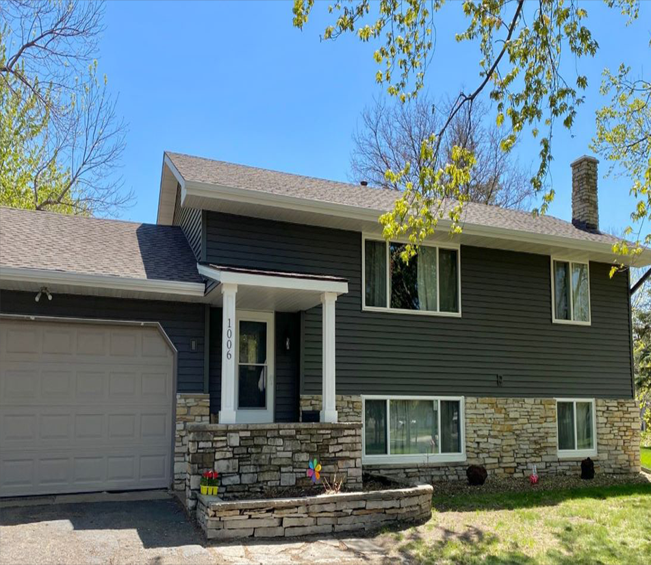 Completed dark gray siding with stone accents on a split-level Minnesota home