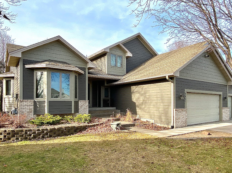 Completed gray lap siding with dark trim and stone accents on a gabled Minnesota home
