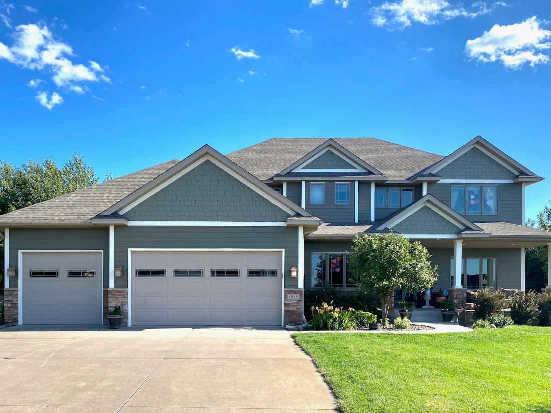 Completed two-tone gray siding on a two-story Minnesota home with a three-car garage