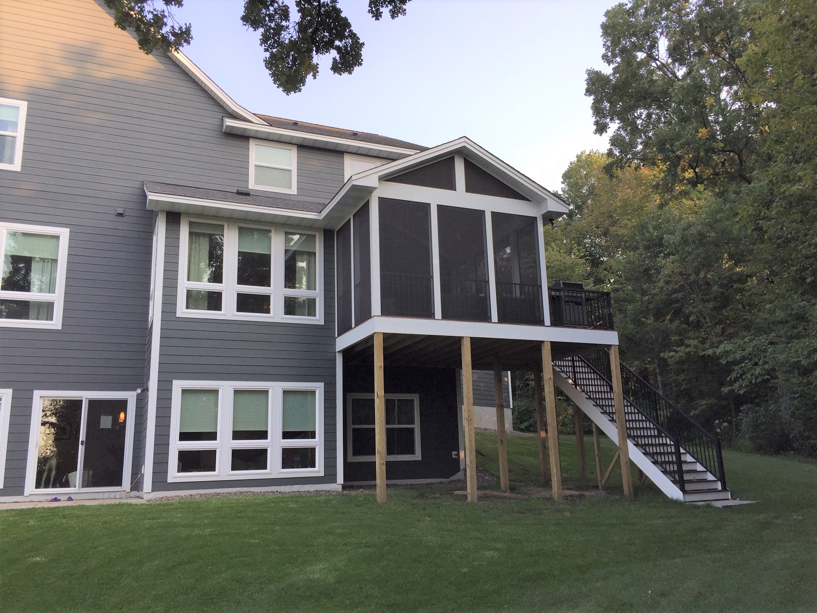 Elevated screened porch addition designed to match a gray two-story home