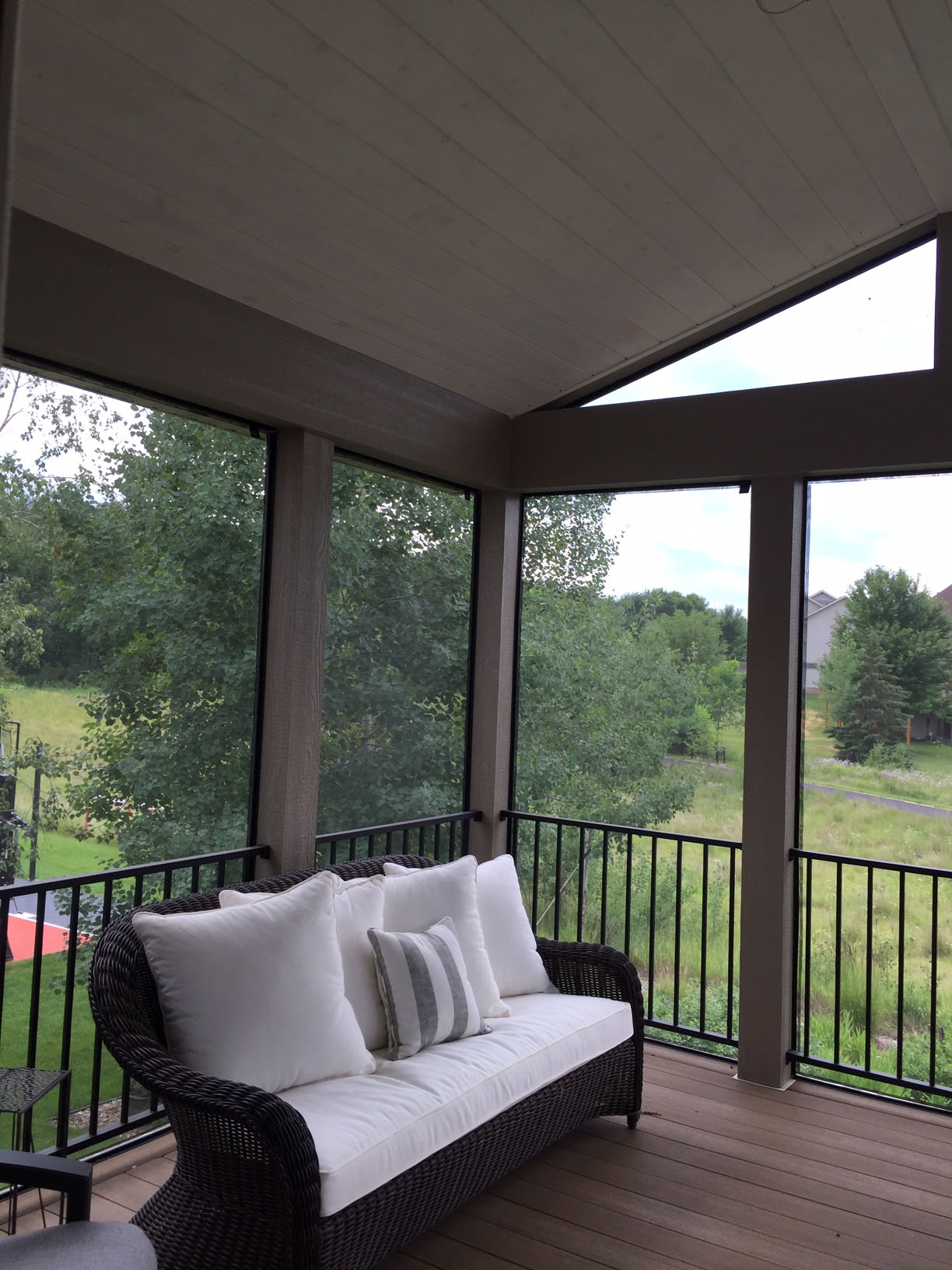 Screened porch with large openings overlooking a green Minnesota landscape