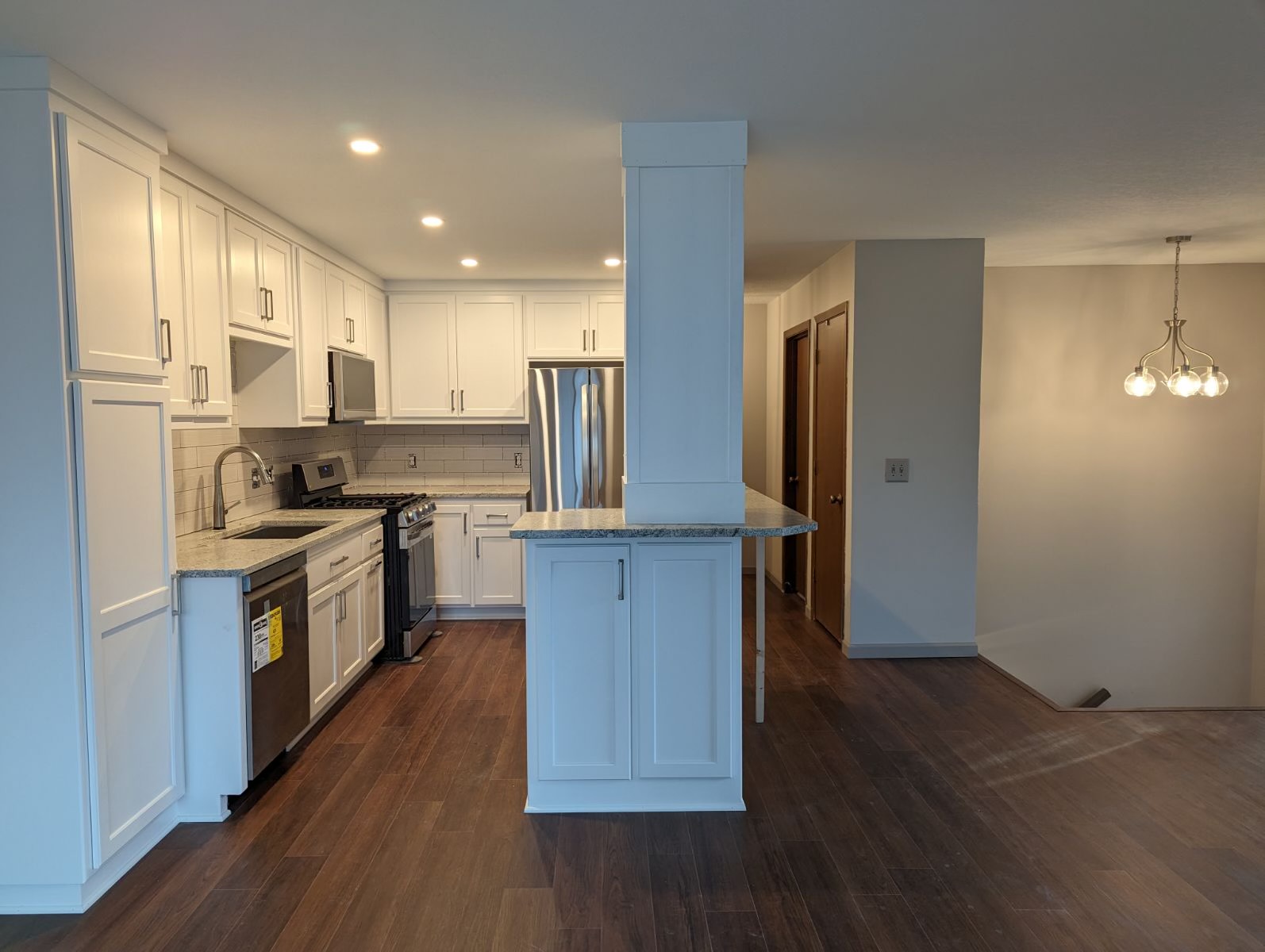 Completed white kitchen with hardwood floors after renovation