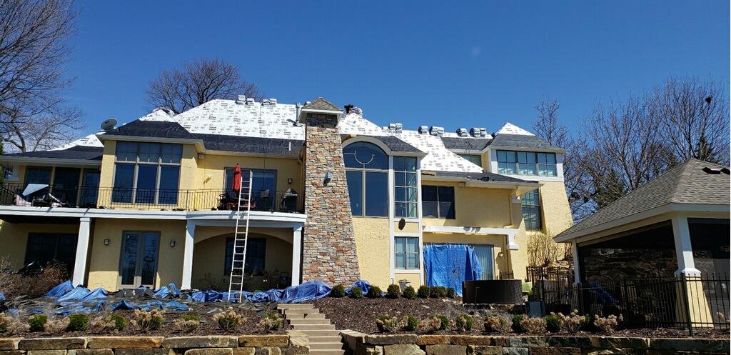 Roof replacement underway on a large lakeside Minnesota home
