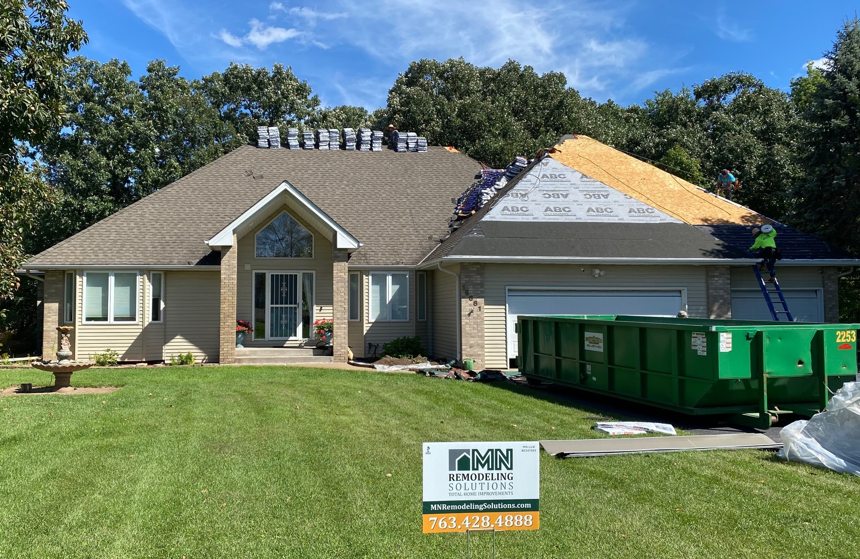 Roofing crew replacing asphalt shingles on a suburban Minnesota home